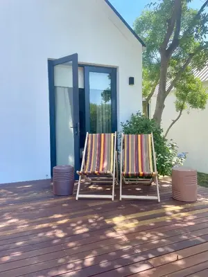 two lawn chairs sitting on a deck in front of a house at Mountain Cottages at Haskell Vineyard in Stellenbosch