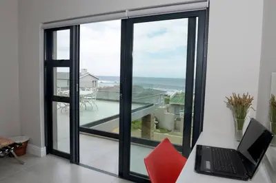 a laptop sitting on a desk in front of a window at The Whale and Waddler - Unit with a view in Kleinmond