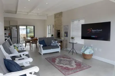 a living room with chairs and a flat screen tv at The Whale and Waddler - Unit with a view in Kleinmond