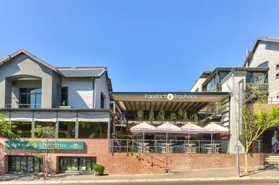 a building with a restaurant with umbrellas on a street at Heritage Square Apartments in Durbanville