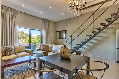 a living room with a table and chairs at Heritage Square Apartments in Durbanville