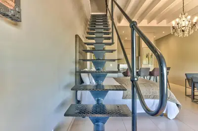 a spiral staircase in a living room with a chandelier at Heritage Square Apartments in Durbanville