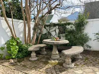 a stone table and two benches in a garden at Courtyard on Weder in Greyton