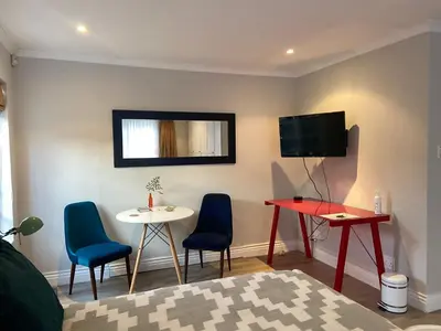 a living room with a table and chairs and a tv at Courtyard on Weder in Greyton
