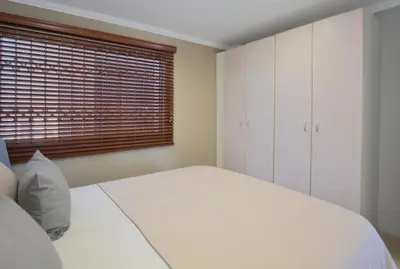 a bedroom with a white bed and a window at 2 Bedroom Oceanfront Apartment with Sea Views in Cape Town
