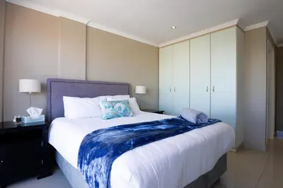 a bedroom with a large bed with a blue blanket on it at 2 Bedroom Oceanfront Apartment with Sea Views in Cape Town