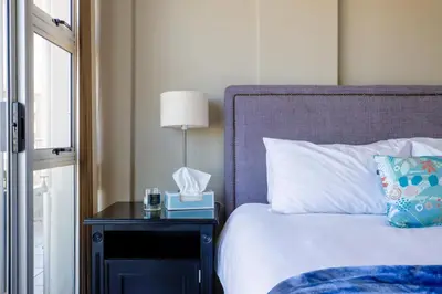 a bedroom with a bed and a night stand with a lamp at 2 Bedroom Oceanfront Apartment with Sea Views in Cape Town