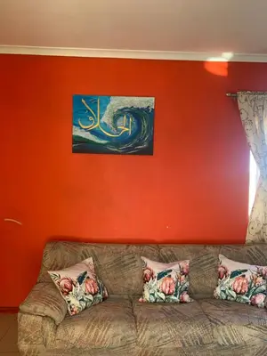 a living room with a couch against a red wall at manu'z in Cape Town