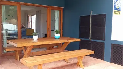 a wooden table and benches in a room at Beach House on 9th in Hermanus