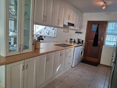 a kitchen with white cabinets and white appliances at Beach House on 9th in Hermanus