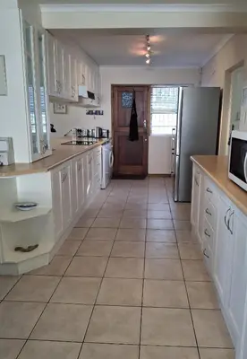 a kitchen with white cabinets and a refrigerator at Beach House on 9th in Hermanus