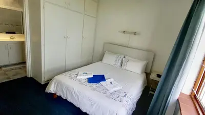 a bedroom with a white bed with a blue book on it at Beach House on 9th in Hermanus