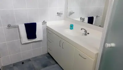 a white bathroom with a sink and a mirror at Beach House on 9th in Hermanus