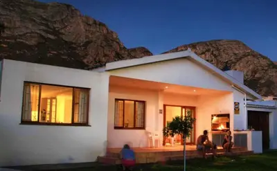 a white house with a mountain in the background at Beach House on 9th in Hermanus