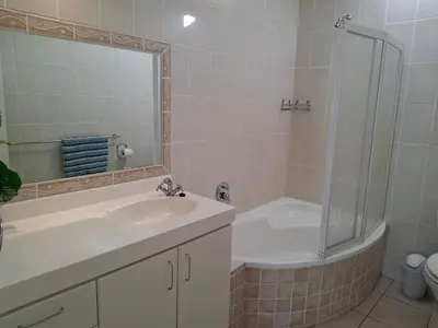 a bathroom with a tub and a sink and a shower at Beach House on 9th in Hermanus
