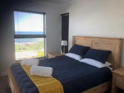 a bedroom with a large blue bed with two pillows at Whale Rock Estate Hermanus sea view apartment in Hermanus