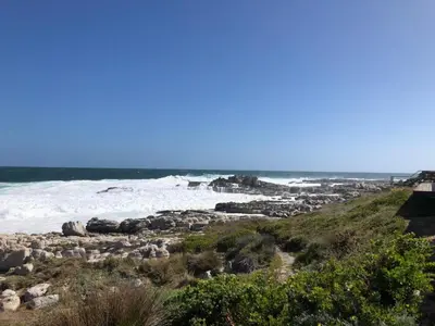 a beach with rocks and waves in the ocean at Whale Rock Estate Hermanus sea view apartment in Hermanus