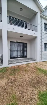 a white house with a balcony and a gate at SEASCAPE MEWS 27 in Cape Town