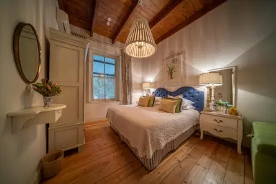a bedroom with a bed with a blue headboard and a mirror at Bartholomeus Klip Farmhouse at Elandsberg Nature Reserve in Hermon