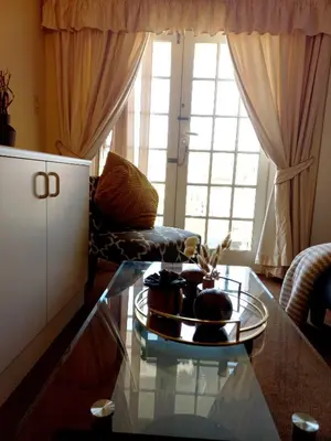 a living room with a glass coffee table in front of a window at Cozy Strand Beach Getaway - Studio Apartment in Cape Town