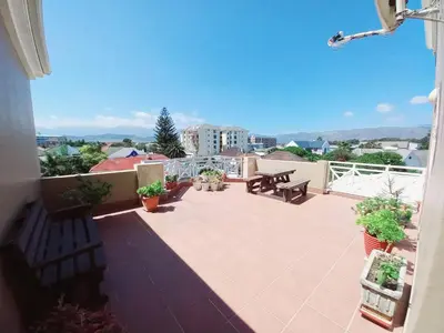 a patio with two benches and a table on a balcony at Cozy Strand Beach Getaway - Studio Apartment in Cape Town