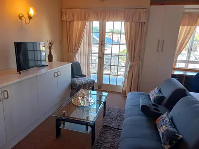 a living room with a blue couch and a tv at Cozy Strand Beach Getaway - Studio Apartment in Cape Town
