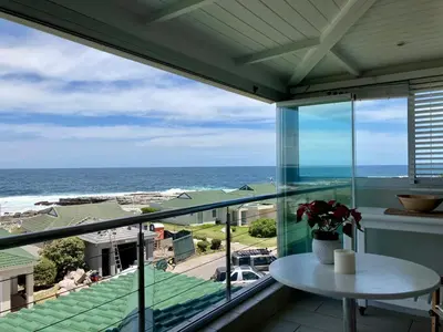a balcony with a table and a view of the ocean at 31 Tobago Bay in Hermanus