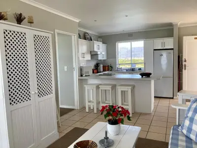 a kitchen with white cabinets and a table in a room at 31 Tobago Bay in Hermanus