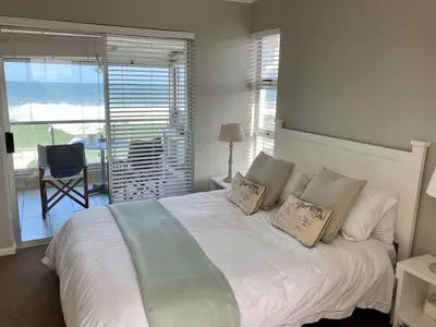 a bedroom with a white bed with pillows and a balcony at 31 Tobago Bay in Hermanus