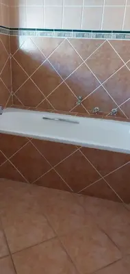 a white bench in a bathroom with a tiled wall at Mestil Guesthouse in Cape Town