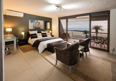 a bedroom with a bed and a balcony at Beach2Anchor, Beachfront 4 bedroom condo with Jacuzzi in Gordonʼs Bay
