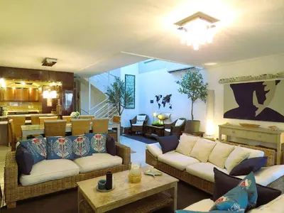 a living room with two couches and a kitchen at Beach2Anchor, Beachfront 4 bedroom condo with Jacuzzi in Gordonʼs Bay
