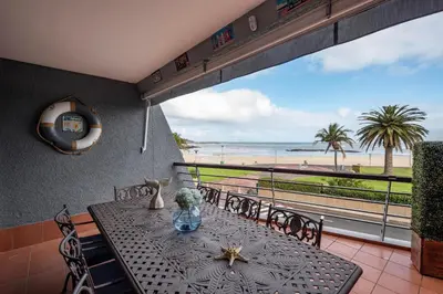 a dining room with a table and a view of the beach at Beach2Anchor, Beachfront 4 bedroom condo with Jacuzzi in Gordonʼs Bay