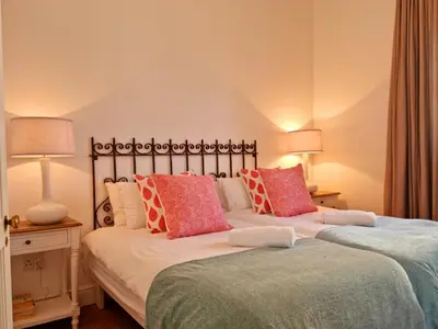 two beds sitting next to each other in a bedroom at Milkwood Cottage, Beachfront family vacation home, Sleeps 6 in Gordonʼs Bay