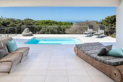 a swimming pool with two couches and a couch at Stamford on Sea by Top Destinations Rentals in Hermanus