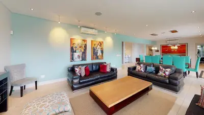 a living room with black leather couches and a table at Stamford on Sea by Top Destinations Rentals in Hermanus