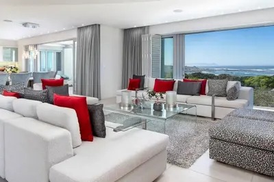 a living room with white furniture and red pillows at Stamford on Sea by Top Destinations Rentals in Hermanus