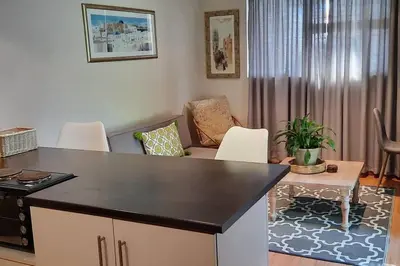a living room with a table and chairs at Home On Uitvlugt - Peaceful leafy garden flat with sunny lounge in Cape Town