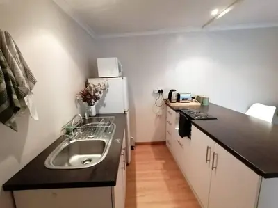 a small kitchen with a sink and a refrigerator at Home On Uitvlugt - Peaceful leafy garden flat with sunny lounge in Cape Town