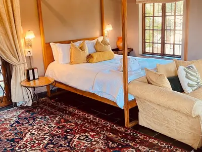 a bedroom with a bed and a couch at Boord Guest House in Stellenbosch