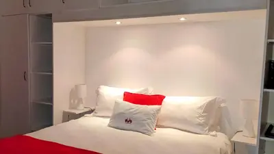 a bedroom with a white bed with red and white pillows at Saxenburg Wine Farm in Kuilsrivier