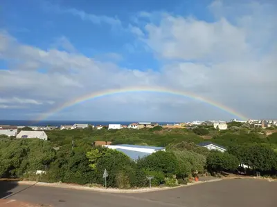 a rainbow in the sky over a city at 41 on Siffie in Hermanus