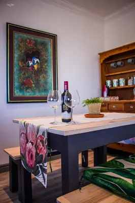 a table with two wine glasses and a painting at 41 on Siffie in Hermanus