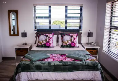 a bedroom with a large bed with pink pillows at 41 on Siffie in Hermanus
