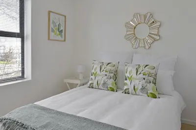 a white bed with pillows and a mirror on the wall at 108 Waverley in Cape Town