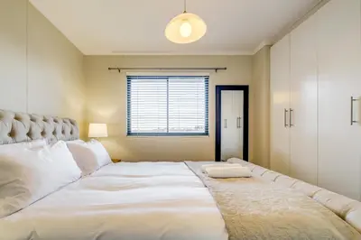 a large white bed in a room with a window at Quayside Canal Eden Home in Cape Town