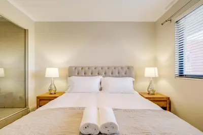 a bedroom with a large white bed with two lamps at Quayside Canal Eden Home in Cape Town