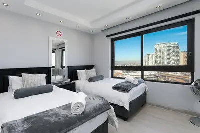 a bedroom with two beds and a large window at Luxury Witsand 706 in Cape Town