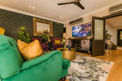 a living room with a green couch and a tv at SW1 Lodge in Somerset West