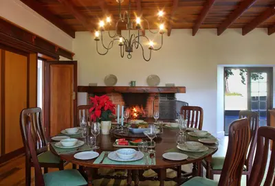 a dining room with a table and a fireplace at Jardin de la Ferme in Franschhoek